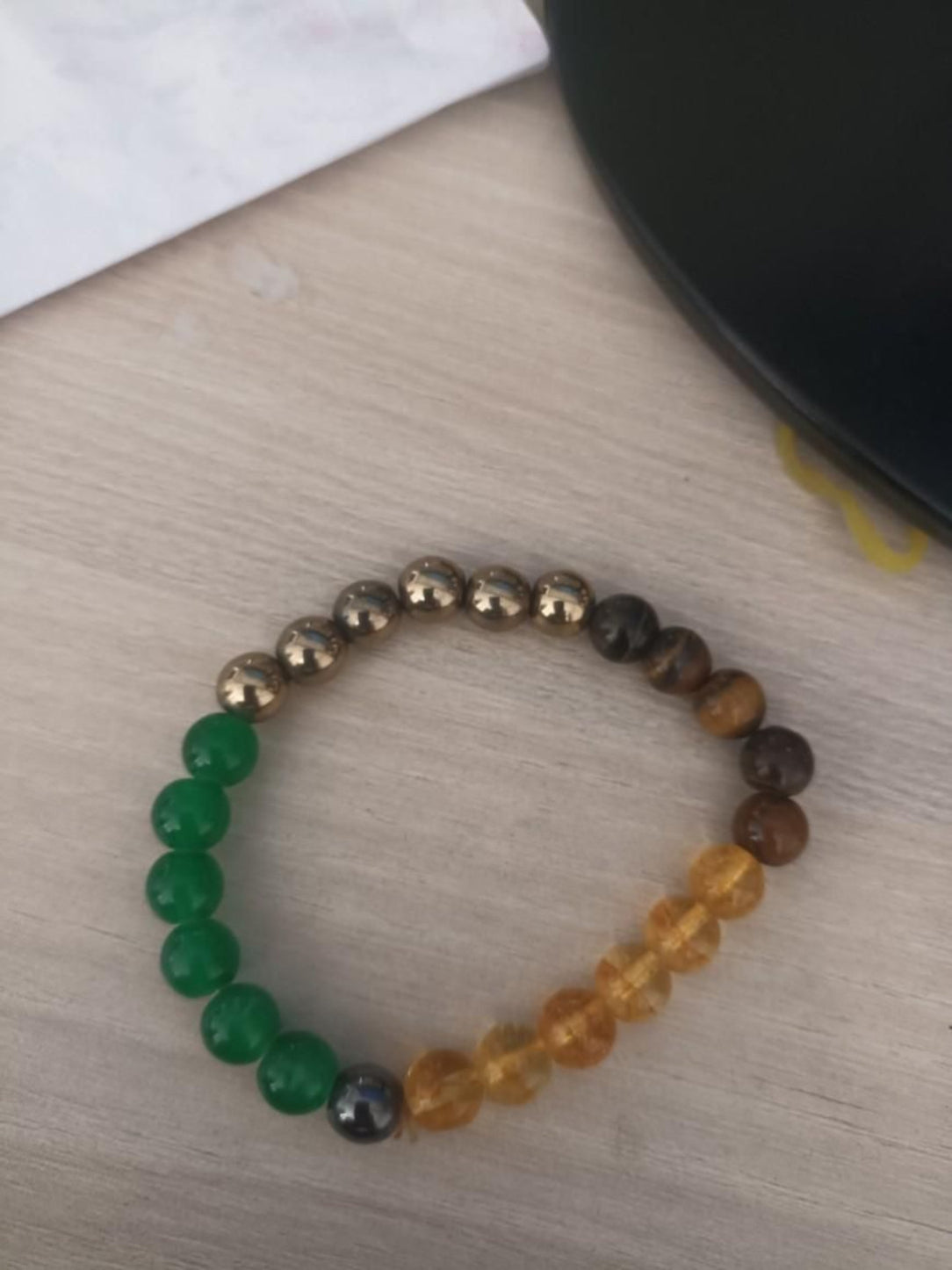 Money Magnet beaded bracelet on a light wooden surface