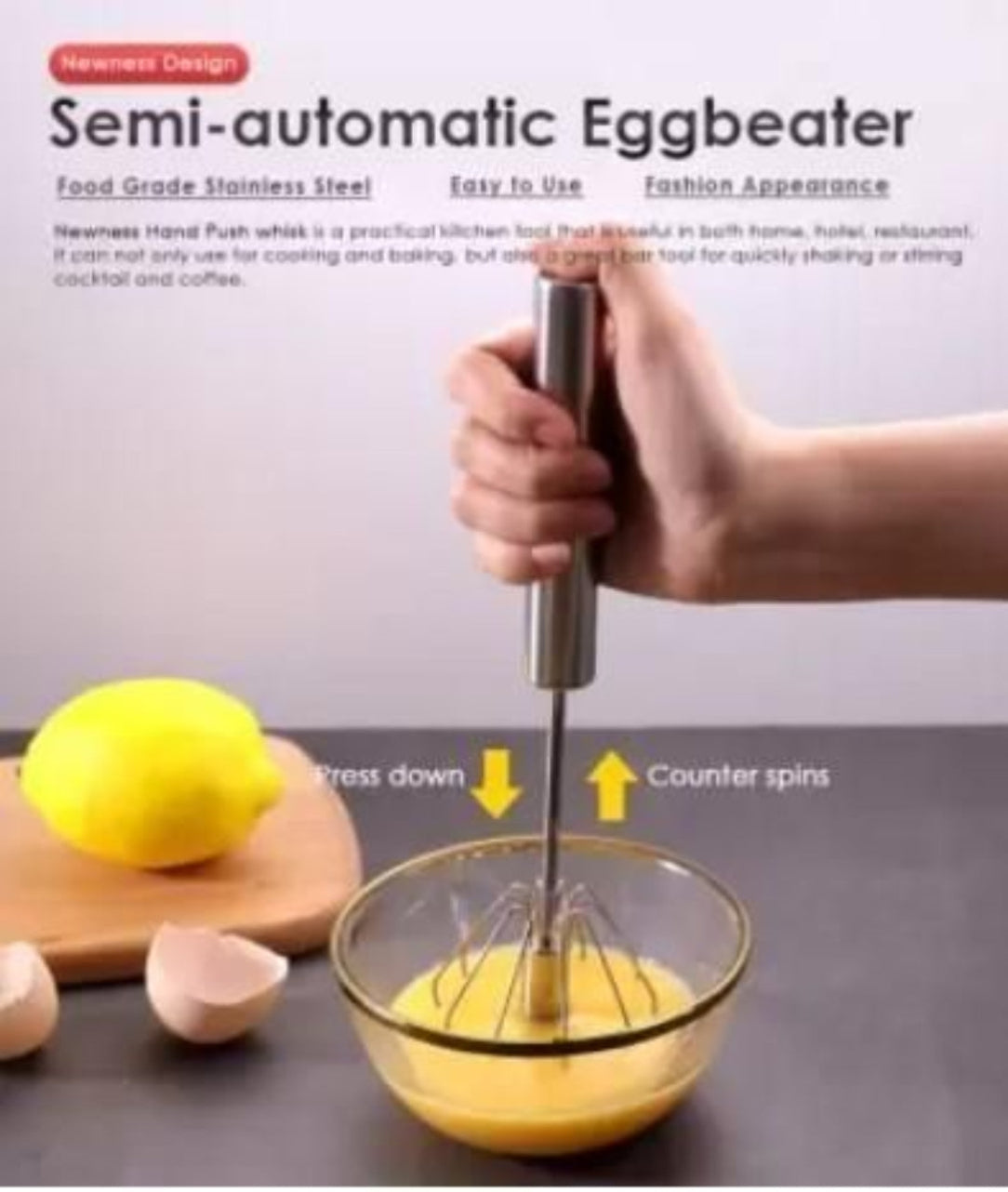 Semi-automatic eggbeater being used to whisk eggs with a lemon and wooden board in the background.