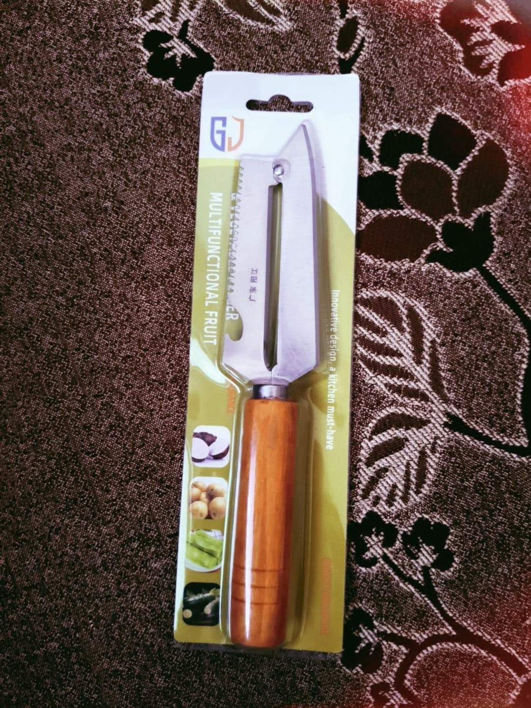 Fruit peeler with wooden handle on a floral-patterned fabric background