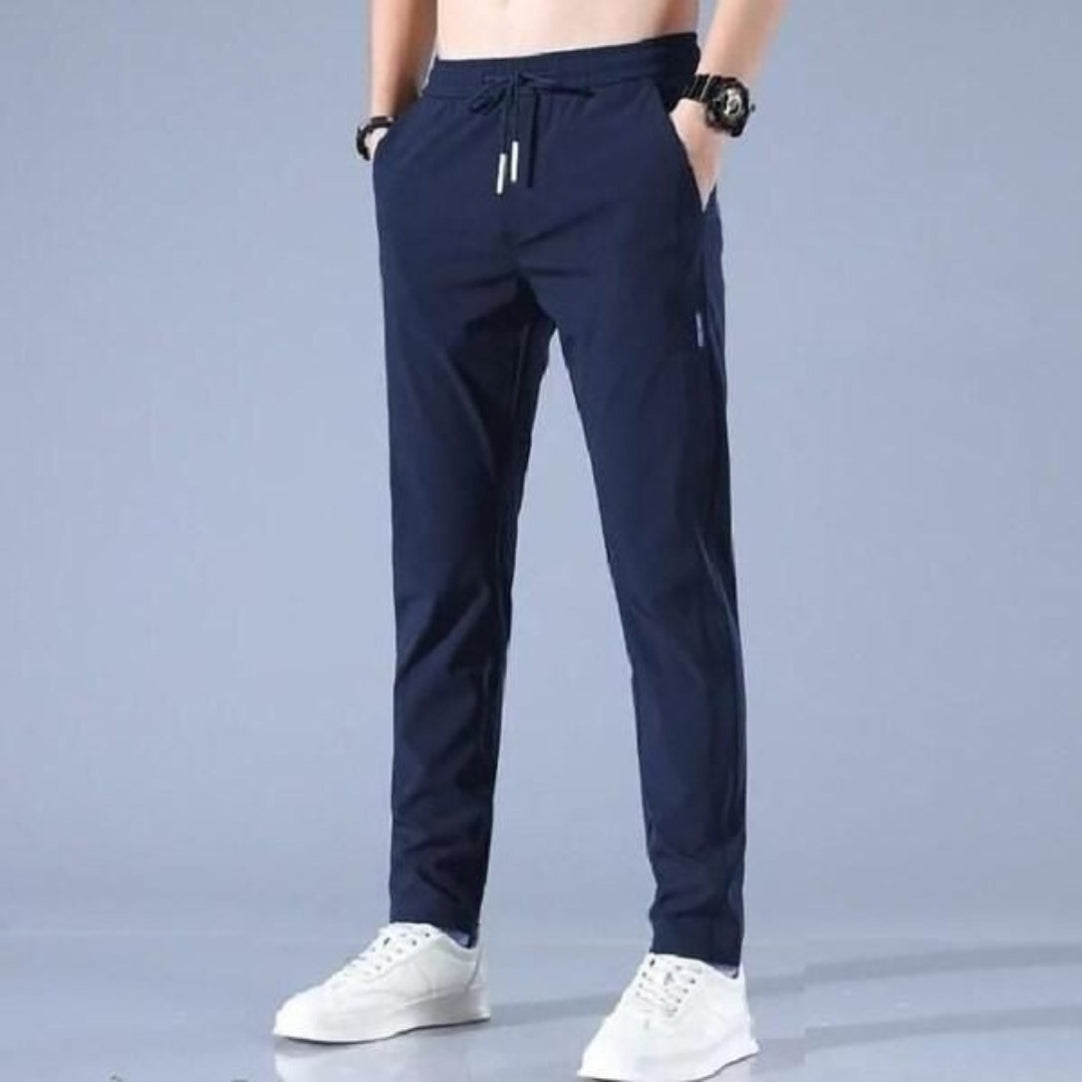 Navy blue jogger pants worn by a person on a gray background