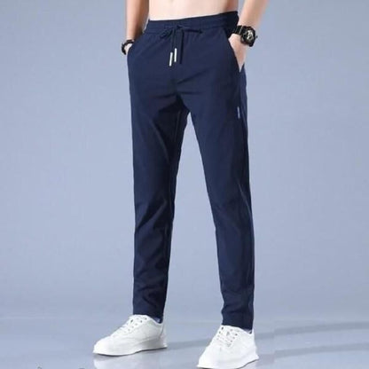 Navy blue jogger pants worn by a person on a gray background