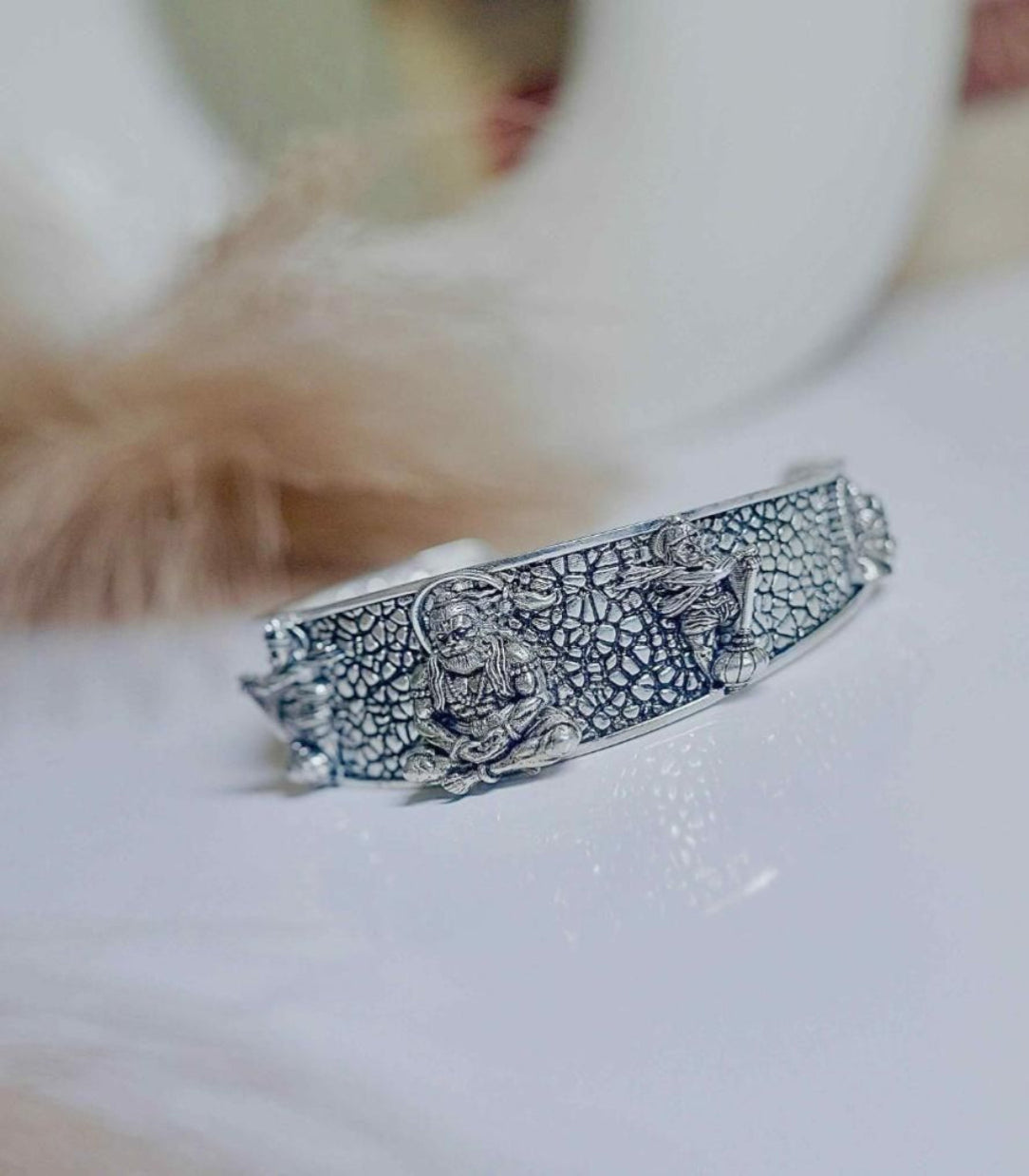 Silver bracelet with intricate design on a white surface