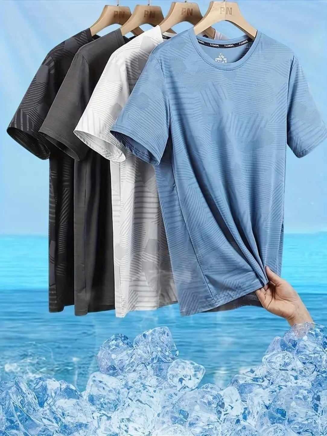 Set of t-shirts in black, white, and blue hanging on a rack with a blue water background.