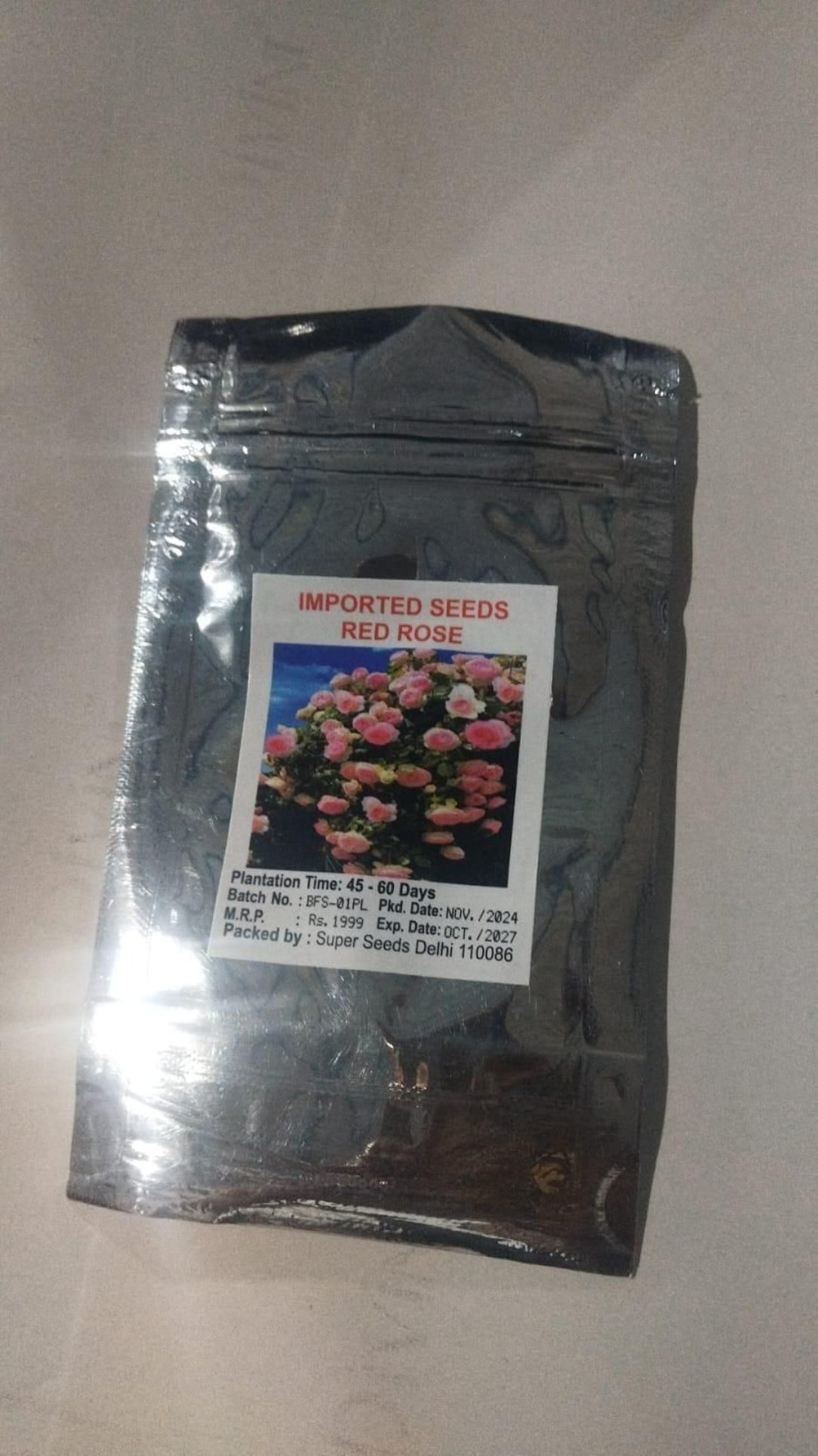 Black package of imported seeds with a label featuring flowers on a light gray background