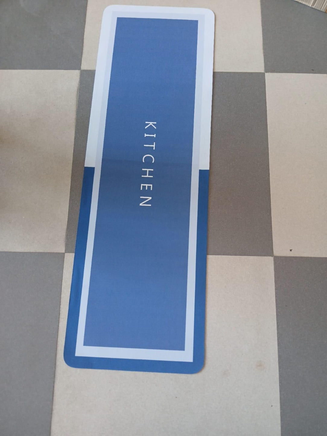 Blue mat with 'KITCHEN' text on a checkered floor