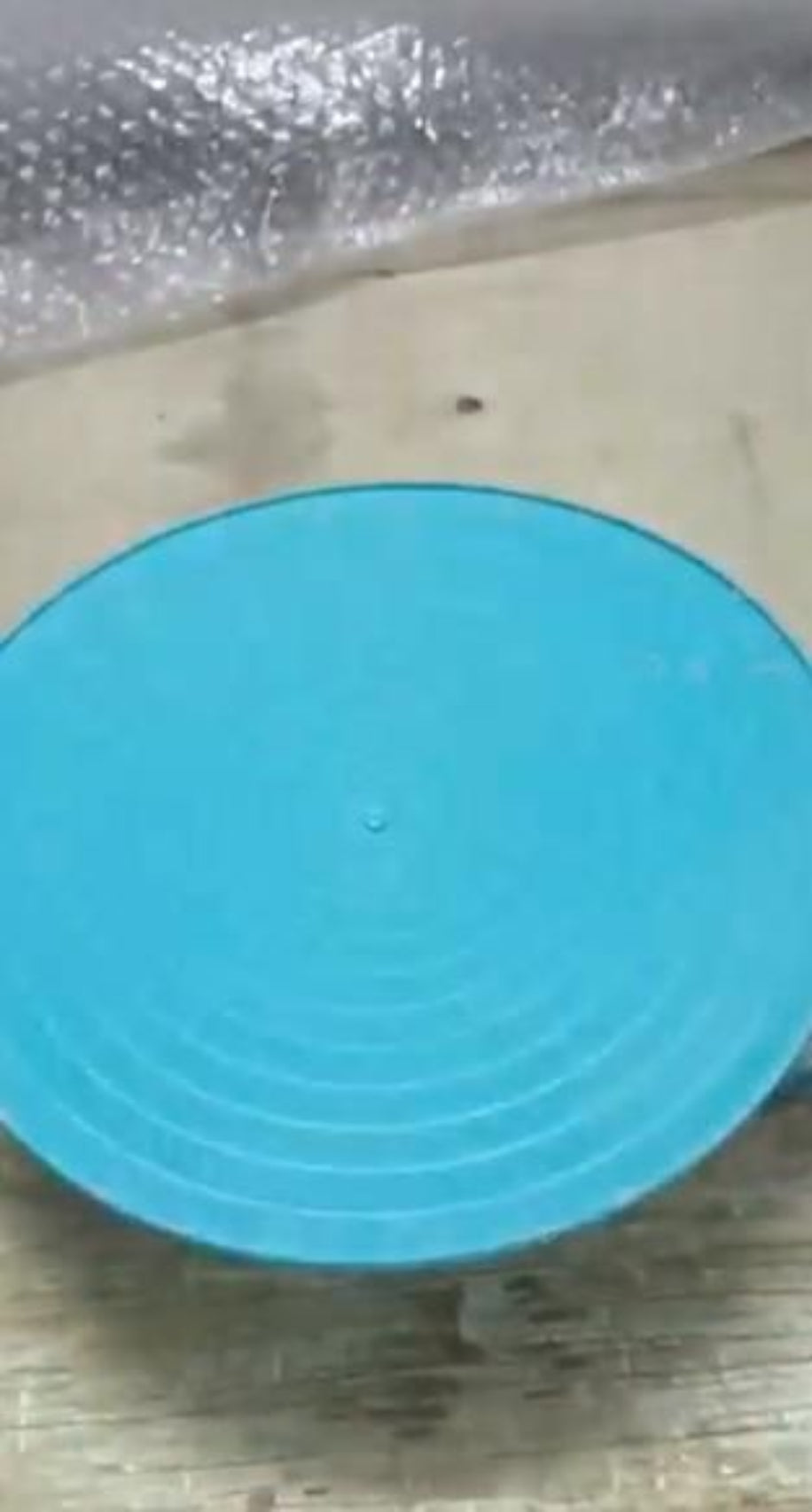 Blue circular object on a textured surface with bubble wrap in the background