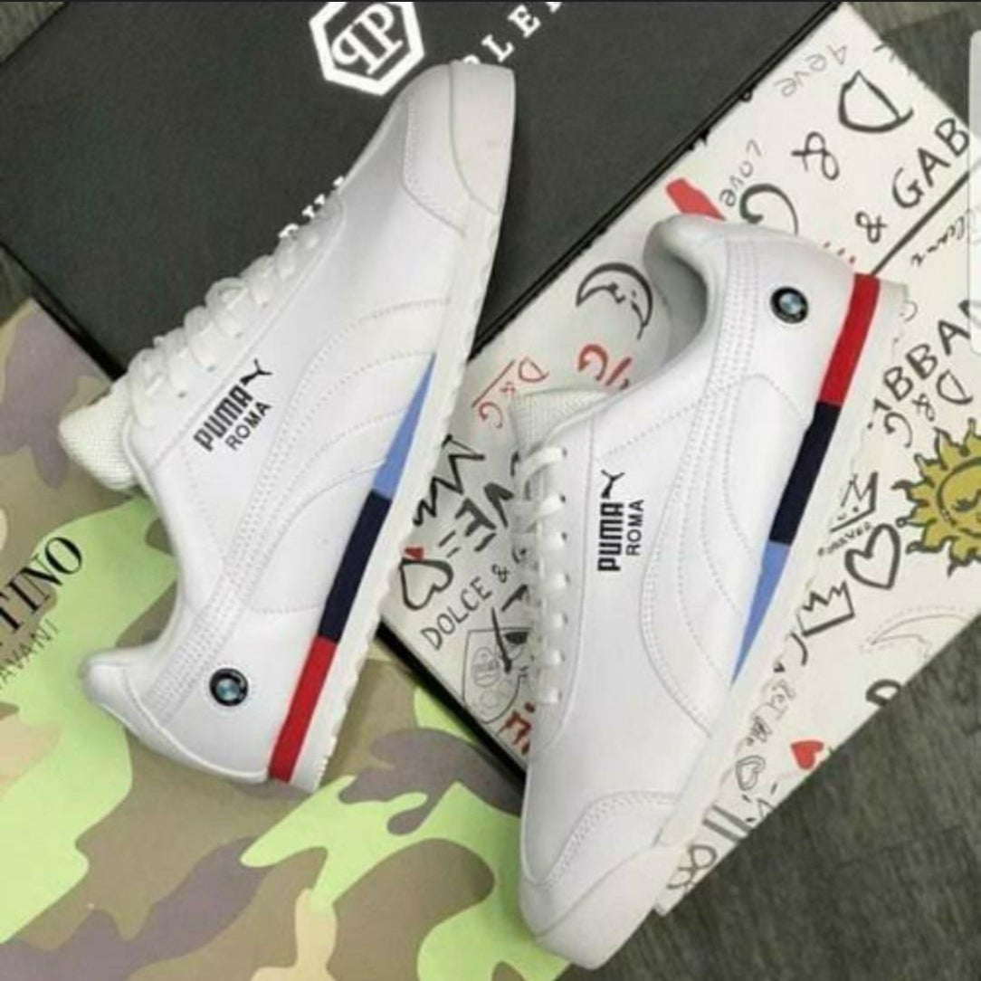 White Puma sneakers with colorful soles on a patterned surface