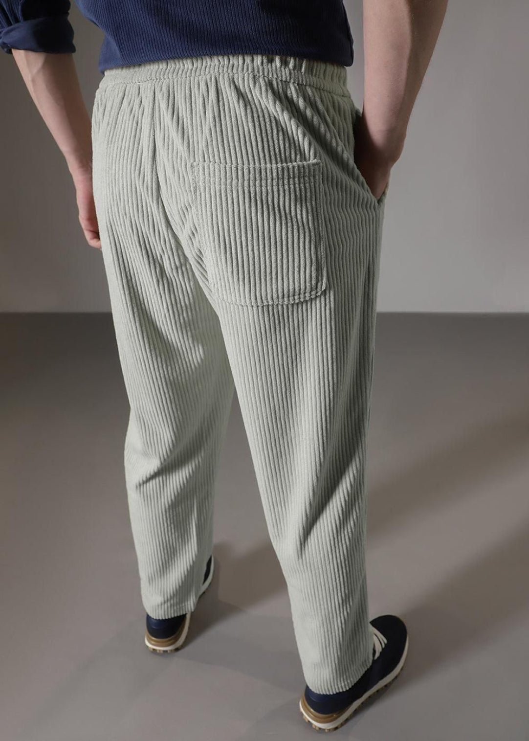 Person wearing light green striped pants on a plain background