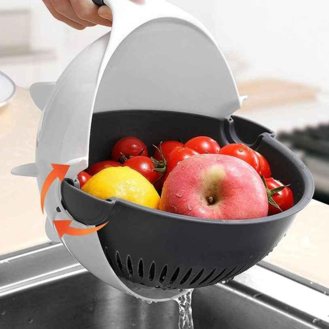 Colander with fruits and vegetables being rinsed under running water in a kitchen sink.