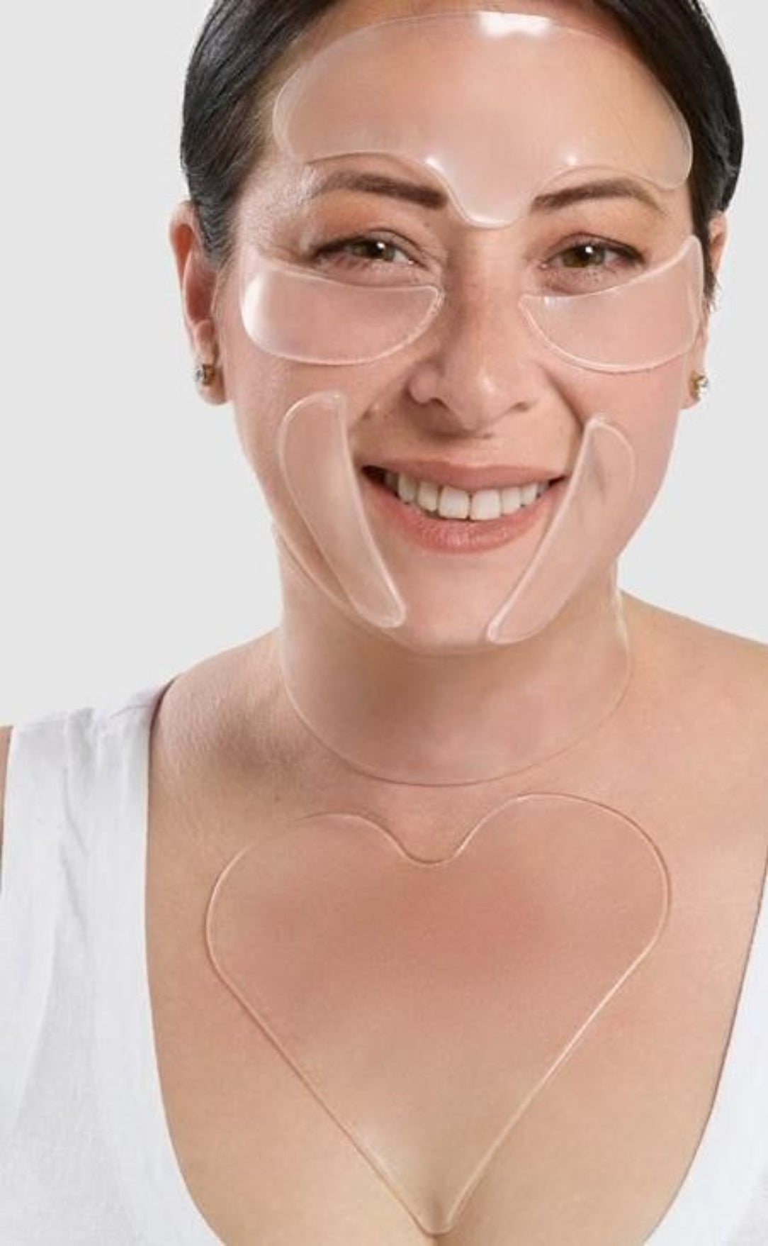 Woman wearing a clear face mask with heart-shaped silicone patches on a white background