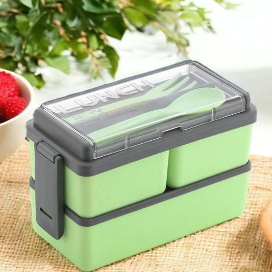 A green Bento Compartment Lunch Box with multiple compartments, secured with a gray lid, containing cutlery and fruits.
