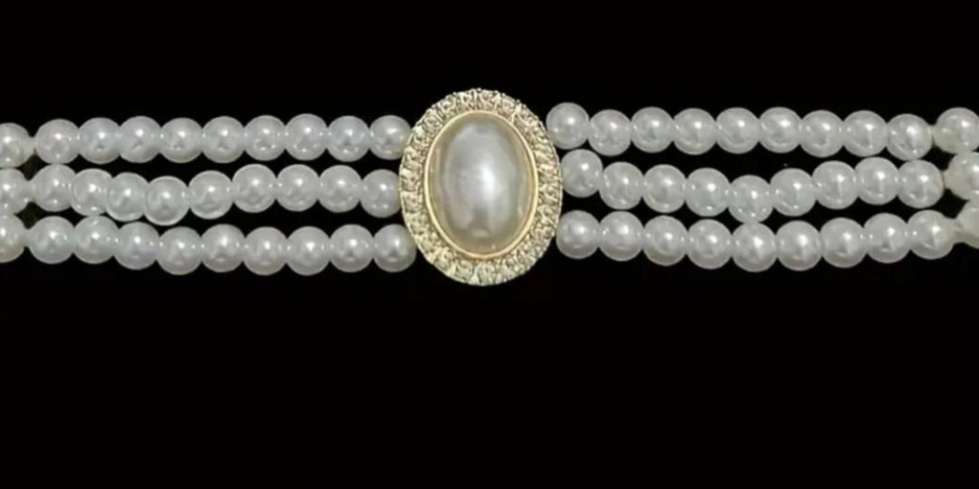 Three-strand pearl necklace with a central pearl pendant on a black background