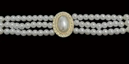 Three-strand pearl necklace with a central pearl pendant on a black background