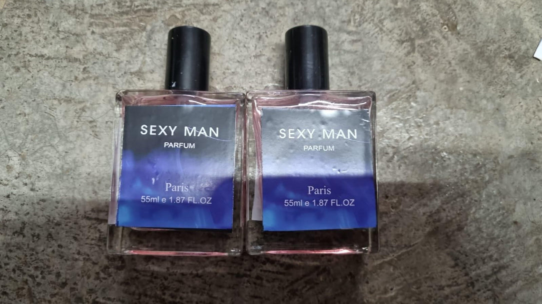 Two bottles of 'Sexy Man' perfume on a concrete surface