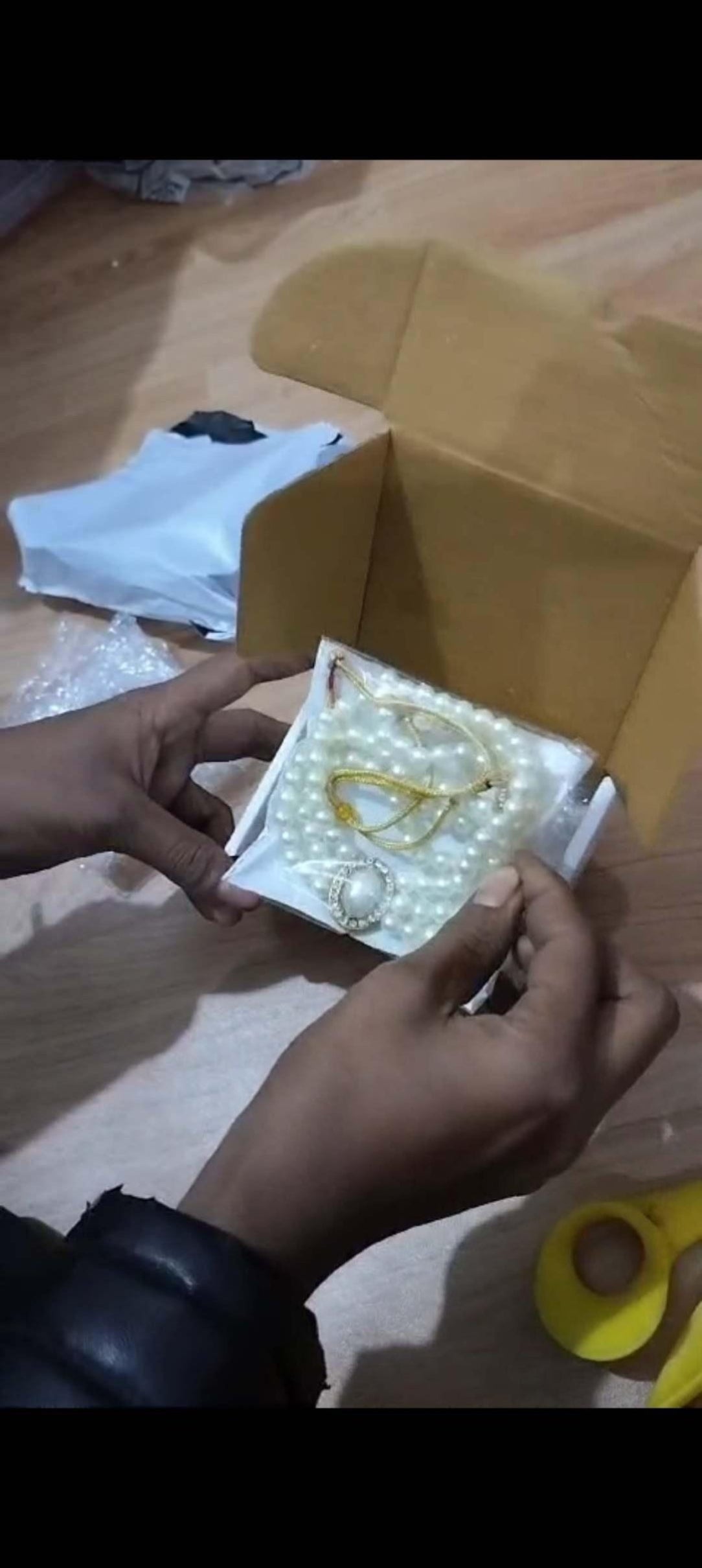 Person holding a small box with jewelry on a wooden surface