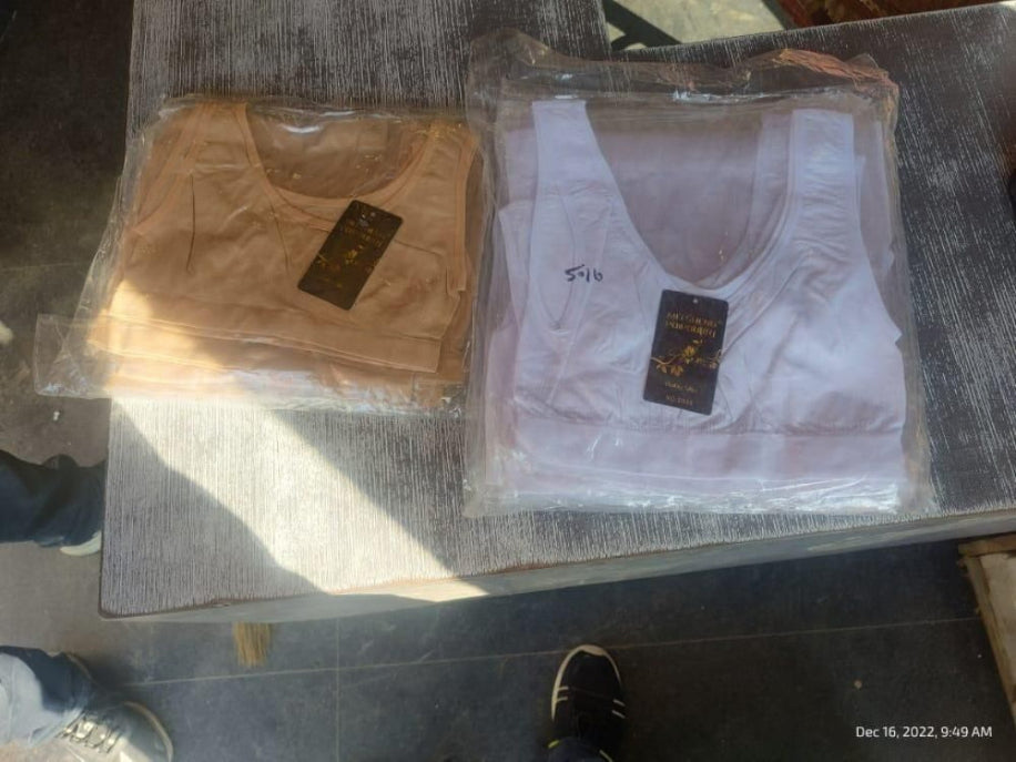 Two vests, one brown and one white, on a dark surface with visible brand labels.