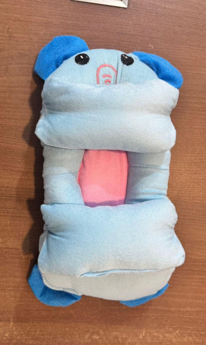 Plush toy resembling a blue and white creature with a pink interior on a wooden surface