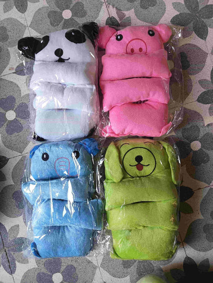 Four animal-themed baby diapers in plastic packaging on a patterned surface.
