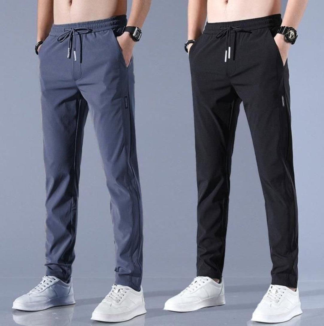 Two models wearing track pants, one in gray and the other in black, both with drawstrings and white sneakers.