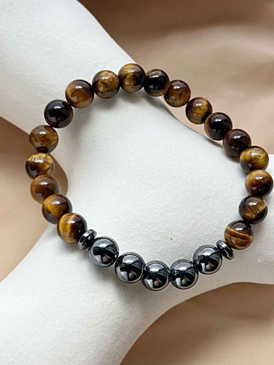 Beaded bracelet with alternating brown and black beads on a white surface