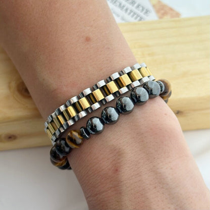 Two bracelets on a wrist with a wooden surface in the background