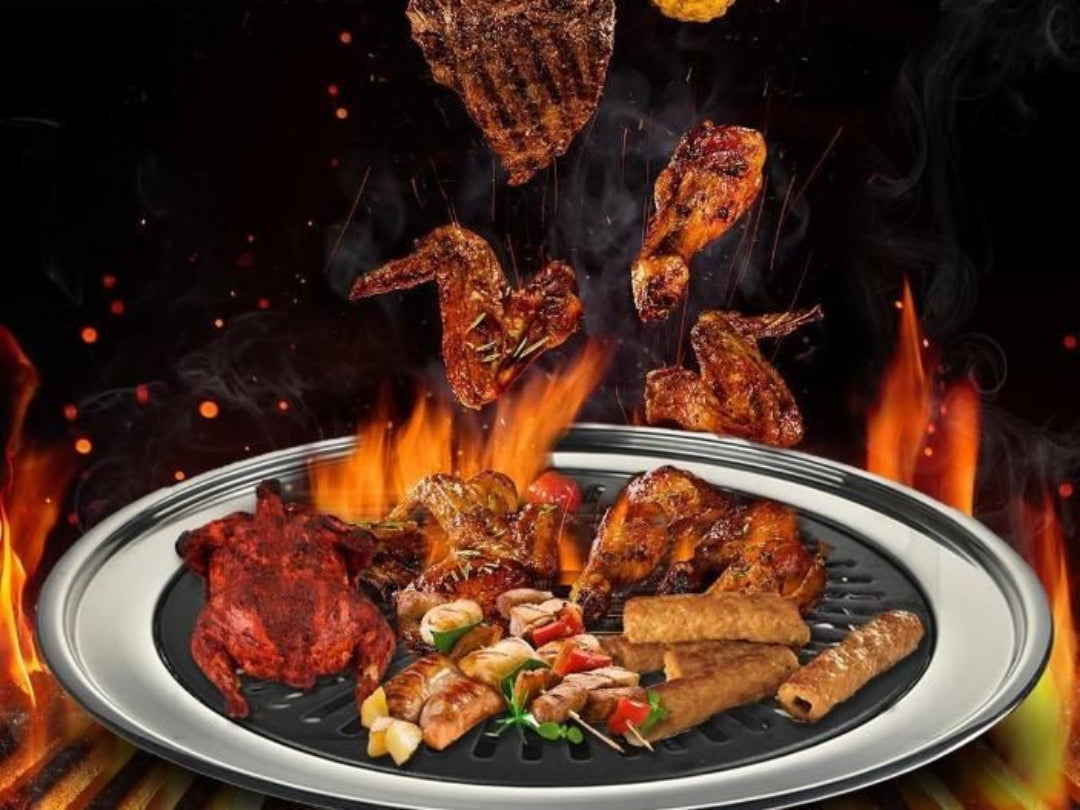 Grilled meats and vegetables on a hotplate with flames in the background