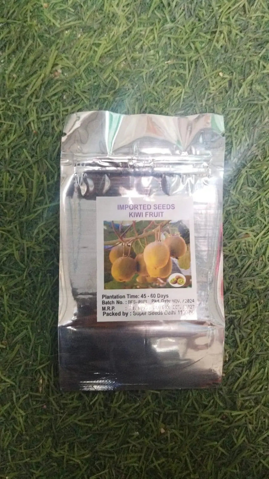 Packaged kiwi fruit seeds on a grass background