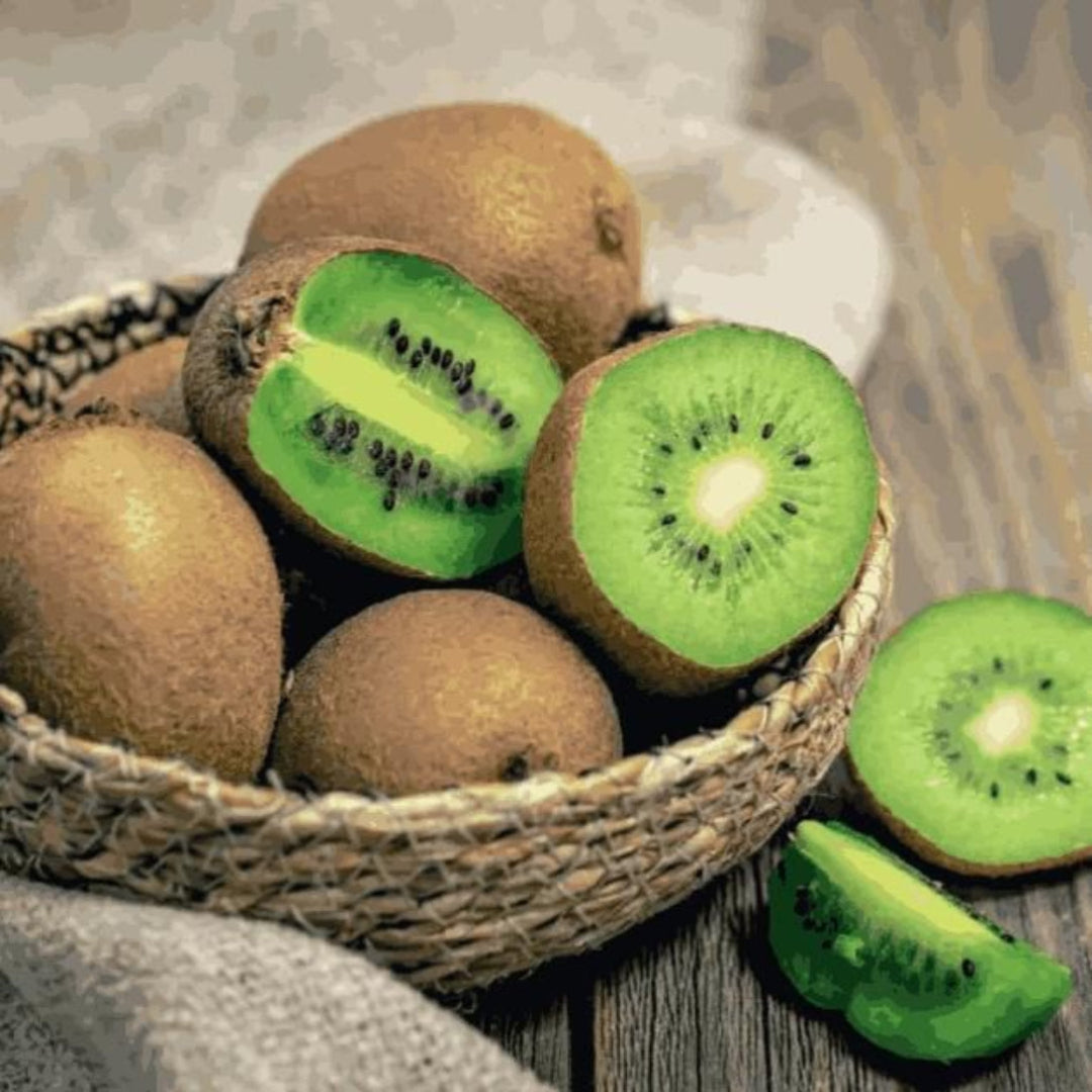 Kiwi fruits, including some sliced open, in a woven basket on a wooden surface.