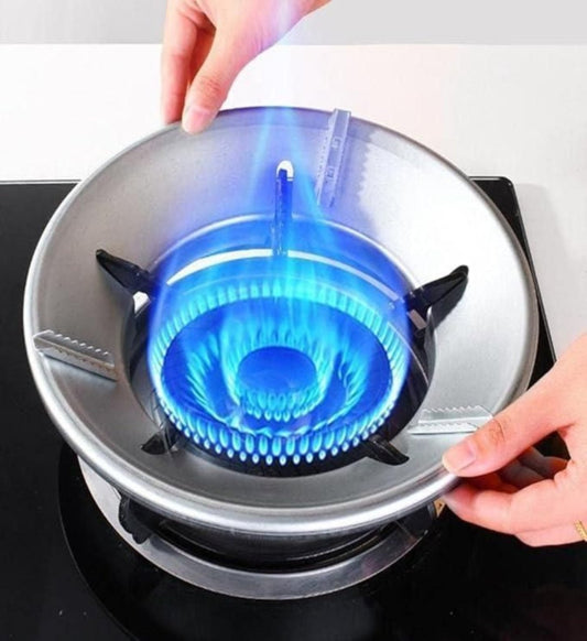 A silver-colored gas saver burner stand with a blue flame, placed on a stovetop.
