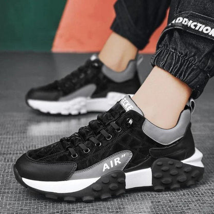 A pair of black casual sneakers with a thick base, lace-up closure, and the brand 'AIR' visible on the shoe.