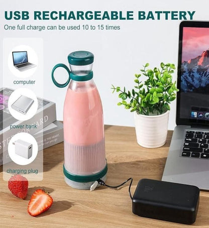 A portable mini USB rechargeable juice blender in pink color, with a green lid and base, displayed on a table alongside a laptop, a power bank, and a strawberry, indicating its compact size and portability.