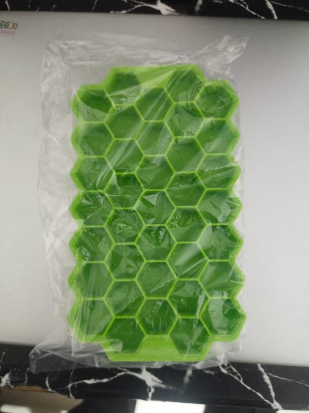 Green honeycomb silicone mold on a white surface with a black marble background