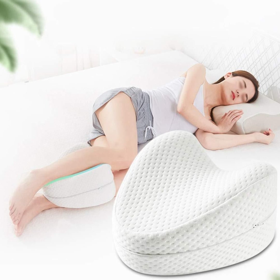 A person is lying on their side on a white knee pillow designed to support the spine.