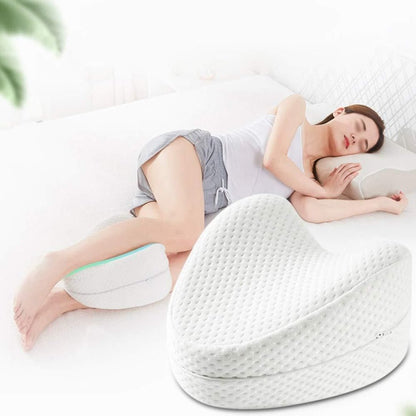 A person is lying on their side on a white knee pillow designed to support the spine.