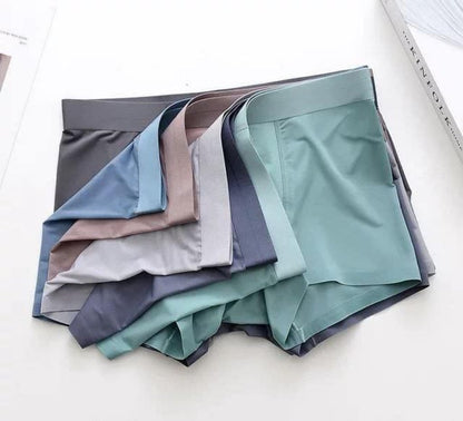 A collection of Men's Ice Silk Briefs Boxers in various solid colors neatly folded and displayed on a flat surface.