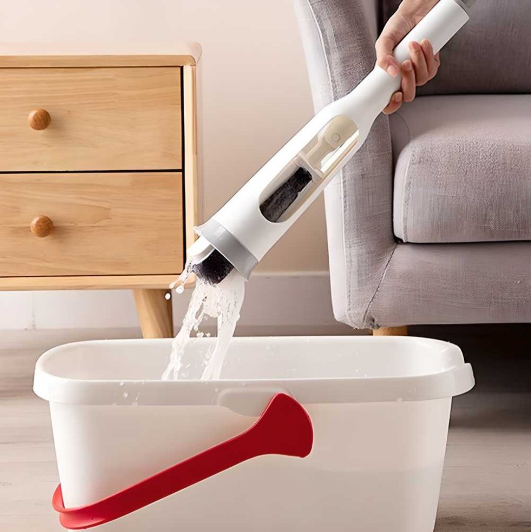 A person is squeezing a white and red folding sponge mop into a white bucket, demonstrating the self-squeezing feature.