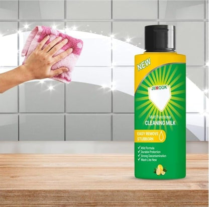 Bottle of Jimook cleaning milk with a hand using a pink cloth on a tiled wall background