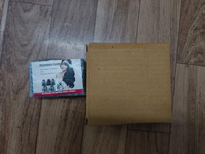 Brown cardboard box on a wooden floor with a business card featuring a woman's face.