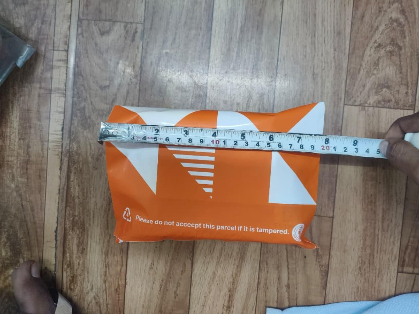 Orange parcel with a measurement tape on a wooden floor