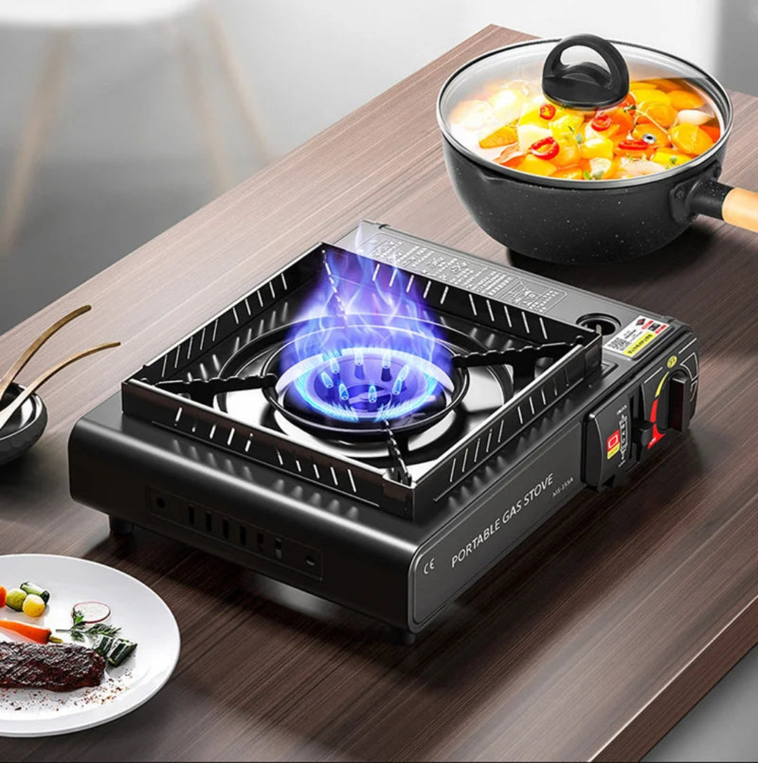Portable gas stove with a pot of food on a wooden table
