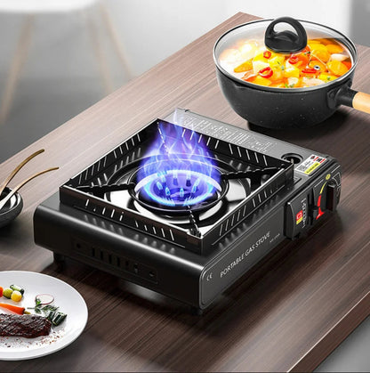 Portable gas stove with a pot of food on a wooden table