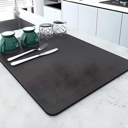 Black placemat on a kitchen counter with cutlery and dishes
