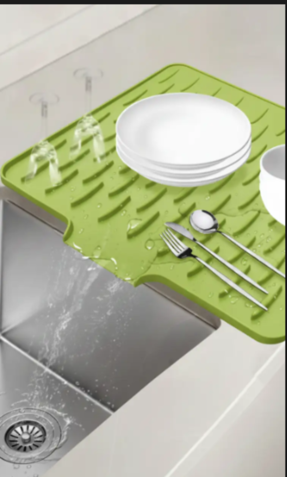 Green silicone mat with dishes on a kitchen counter next to a sink