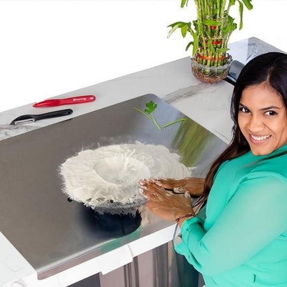 Woman using a cleaning tool on a glass surface with a plant and pen in the background