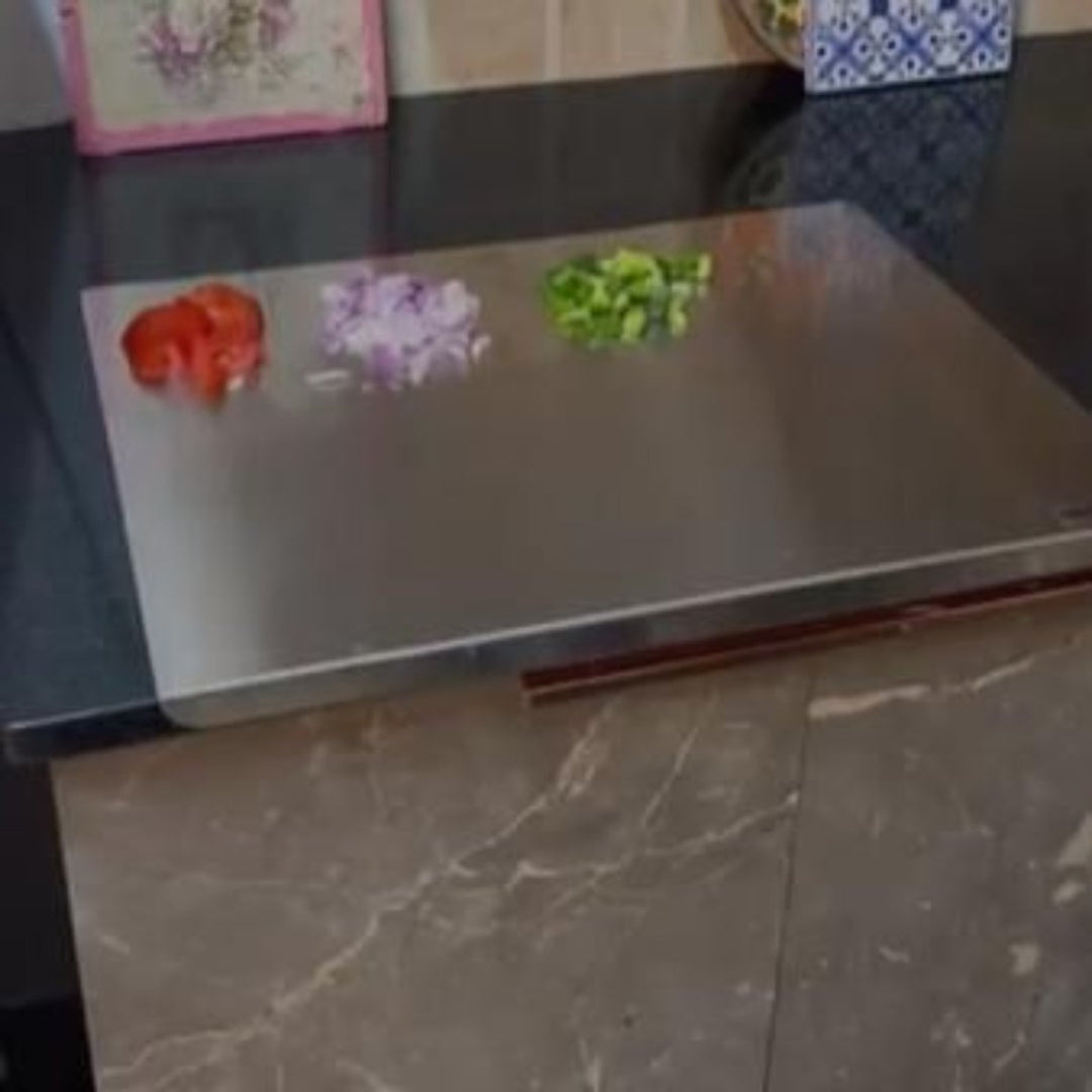Stainless steel cutting board with colorful flower-shaped cutouts on a dark surface.