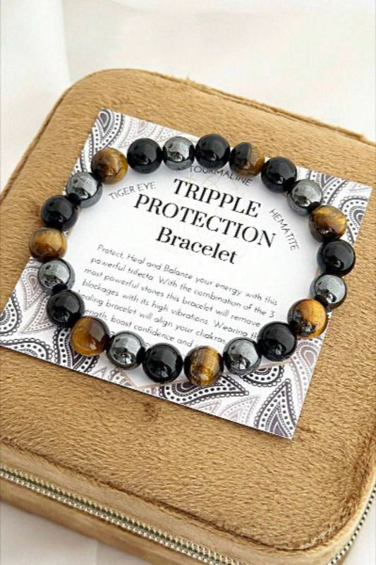 Tripple Protection bracelet on a branded card with a wooden box background