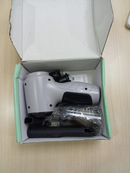 White electronic device with black components inside an open box on a beige surface.