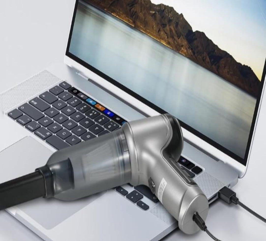 Small handheld vacuum cleaner connected to a laptop on a desk