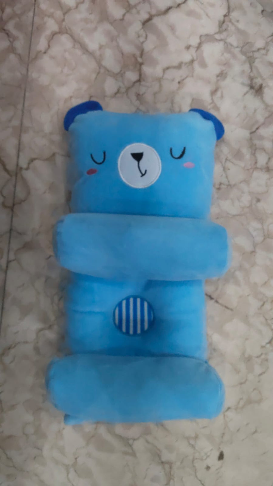 Blue bear-shaped pillow on a marble surface