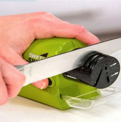 A hand using an electric motorized rotating knife sharpener on a kitchen counter.
